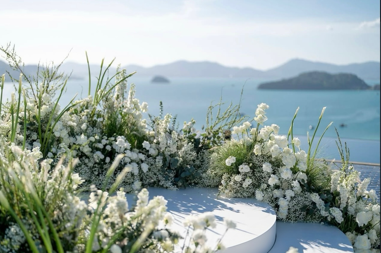 White florals and greenery above the sea
